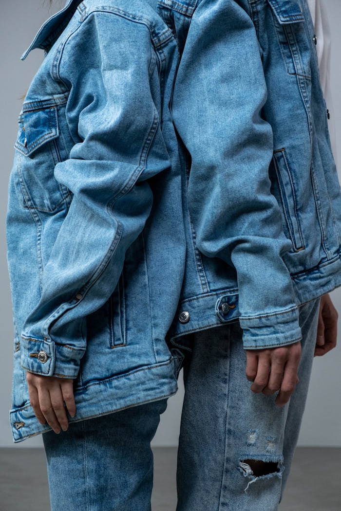 Close-up of two people posing in denim jackets indoors.